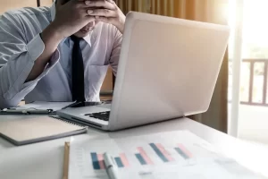 Hombre preocupado frente a laptop por mala reputación online, apoyado por agencia de reputación online en México.